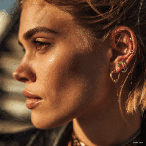 Detalle de un "curated ear" con un piercing Daith con aro, un piercing Rook y un Tragus con brillante, mostrando la tendencia de oreja personalizada.
